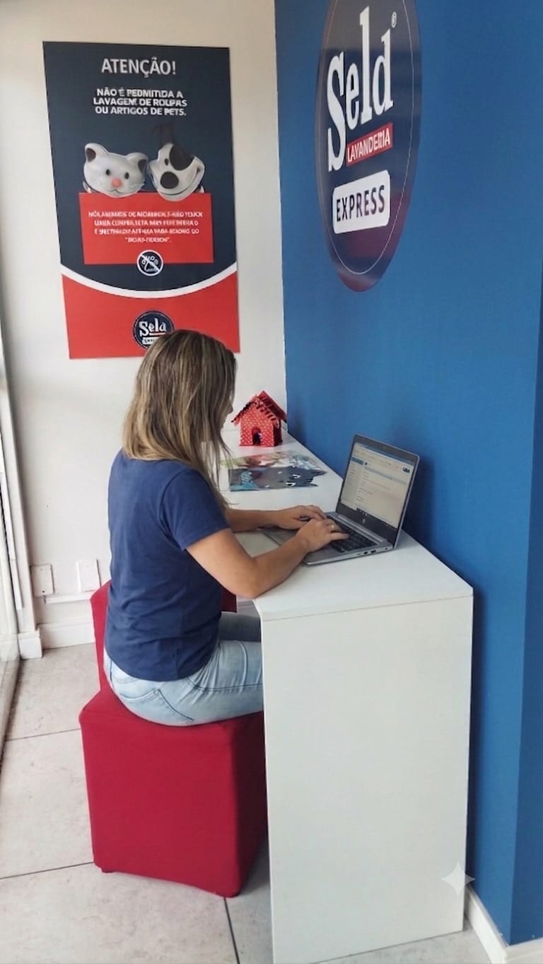 Cliente trabalhando no notebook com wi-fi gratuito na SELD Lavanderia Express